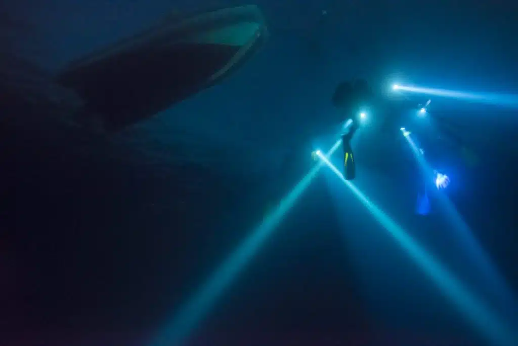 Buceador realizando buceo nocturno en Alicante iluminando el fondo marino con linterna
